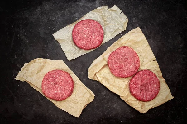 Kağıt Üzerinde Çiğ Hamburger Köfteleri Siyah Arka Plan Genel Bakış — Stok fotoğraf
