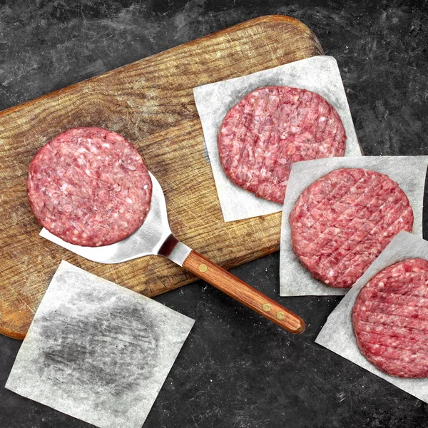 Raw Minced Meat Cutlets. Fresh Raw Minced Beef Pork Steak Burgers. Uncooked Ground Meat Beef Burgers on Wooden Board. Burger Cutlet From Beef Meat. Raw Burger Beef Patty On Black Wooden Background.