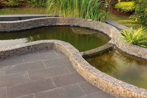 花园带人工装饰的小池塘 铺在地板上 园林绿化后院落 四周环绕着帕蒂奥地区的小池塘 细节中的现代后院落景观 — 图库照片