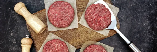 Raw Minced Meat Cutlets. Fresh Raw Minced Beef Pork Steak Burgers. Uncooked Ground Meat Beef Burgers on Wooden Board. Burger Cutlet From Beef Meat. Raw Burger Beef Patty On Black Wooden Background.