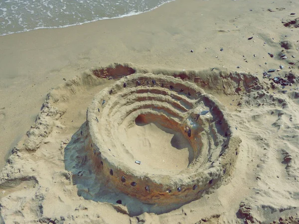 Sand Castle On A Sandy Beach. Sandcastle In The Shape Of Italian Colosseum. Family Or Children Creativity On Sea Summer Vacation Or Holiday.