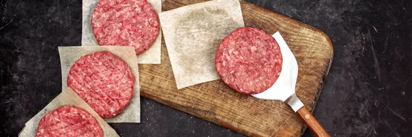 Raw Minced Meat Cutlets. Fresh Raw Minced Beef Pork Steak Burgers. Uncooked Ground Meat Beef Burgers on Wooden Board. Burger Cutlet From Beef Meat. Raw Burger Beef Patty On Black Wooden Background.