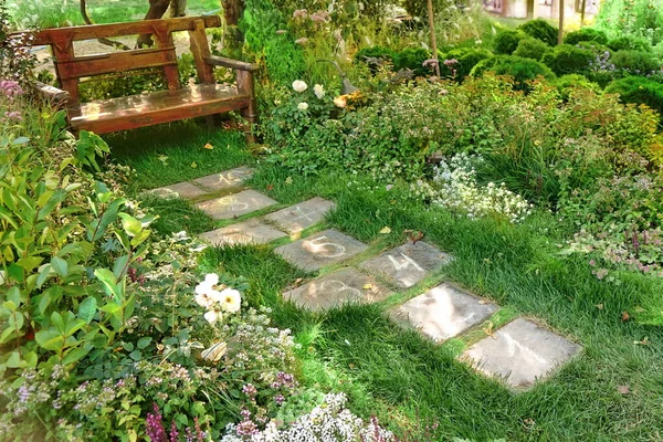 Garden landscaping Path to Wooden Bench with Hopscotch Play Game Place.  Landscaped Backyard Garden. Decorative Garden Landscaping With Stony Tilled Path.