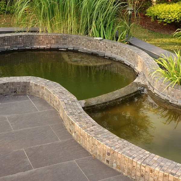 花园带人工装饰的小池塘 铺在地板上 园林绿化后院落 四周环绕着帕蒂奥地区的小池塘 细节中的现代后院落景观 — 图库照片