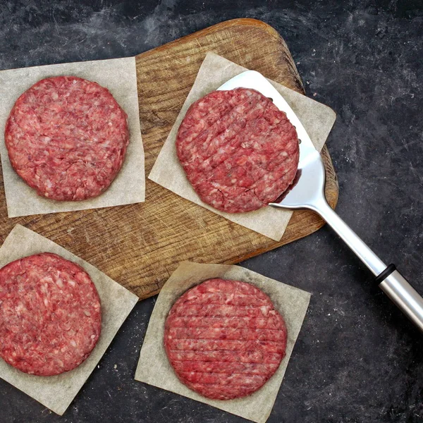 Raw Minced Meat Cutlets. Fresh Raw Minced Beef Pork Steak Burgers. Uncooked Ground Meat Beef Burgers on Wooden Board. Burger Cutlet From Beef Meat. Raw Burger Beef Patty On Black Wooden Background.