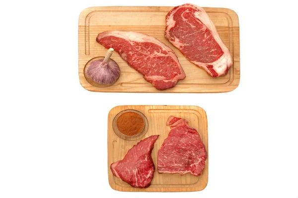 在白色背景上隔离的木板上的胡椒和条带素牛肉炖肉 生苏林牛肉或小牛肉炖白孤立 顶部视图 Tenderloin Beef Steaks Wood Overhead View — 图库照片
