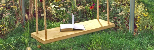 Wooden Swing in Garden with Open Book. Swing in Beautiful Summer Backyard Garden on Warm and Sunny Day Outdoors. Beautiful Garden Vintage Place for Family Rest In Shaded Garden. Romantic Garden Place.