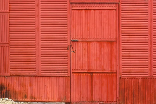 Parede vermelha de metal ondulado enferrujado e porta — Fotografia de Stock