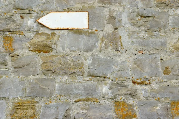 老石头墙上的锈色空白色街箭头指针 — 图库照片