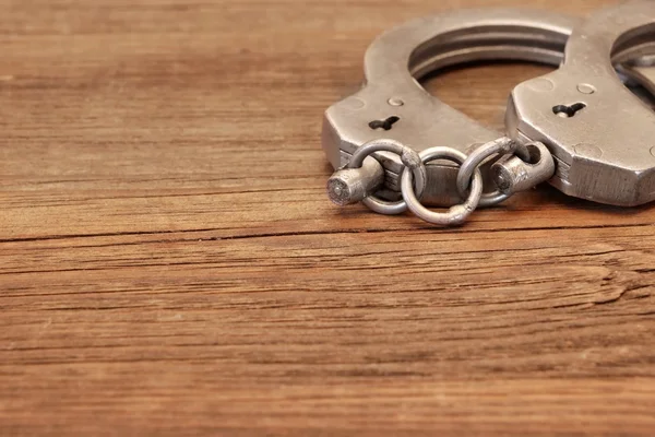 Steel Handcuffs on Wooden Table — Stock Photo, Image