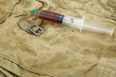 Medical Syringe With Brown Liquid on Camouflage Army Bag clipart