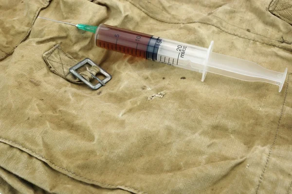 Medical Syringe With Brown Liquid on Camouflage Army Bag — Stock Photo, Image