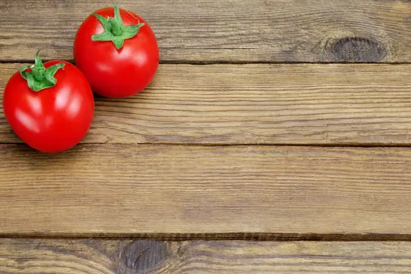 Due pomodori maturi su fondo rustico in legno — Foto Stock