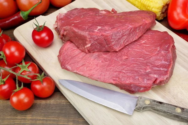 Bife de carne fresca crua dois e tomate close-up — Fotografia de Stock