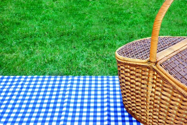 Cesta de piquenique na mesa com toalha de mesa branca azul — Fotografia de Stock