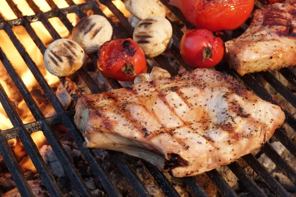 Schweinerippchen-Steaks, Tomaten und Pilze auf heißem Grill — Stockfoto