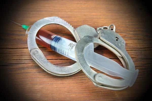 Syringe and Handcuffs On Grunge Wood Background — Stock Photo, Image
