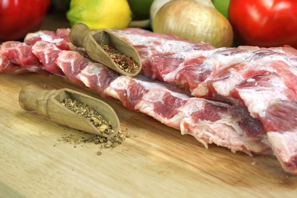 Costillas de repuesto crudas en tablero de corte de madera con especias — Foto de Stock