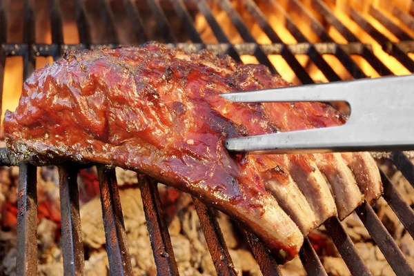 Costillas de repuesto de cerdo en la parrilla de barbacoa de llama caliente — Foto de Stock