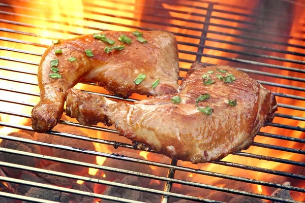 Крупный план двух ног курицы барбекю на горячем пламени гриль — стоковое фото