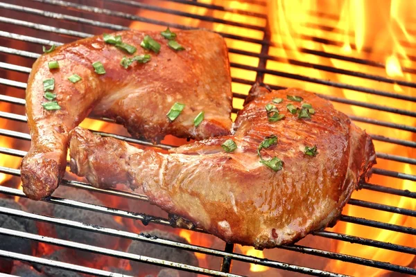 Primer plano de dos patas de pollo barbacoa en la parrilla de llama caliente —  Fotos de Stock