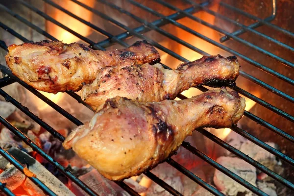 Primer plano de las piernas de pollo barbacoa en la parrilla de llama caliente —  Fotos de Stock