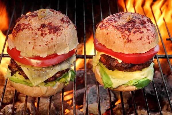 Dos hamburguesas caseras de queso en la parrilla de barbacoa en llamas — Foto de Stock