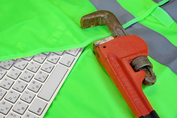 Tastatur in grüner Warnweste und Schraubenschlüssel — Stockfoto