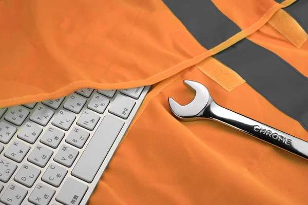 Keyboard In The Orange Reflective Safety Vest And Wrench — Stok fotoğraf