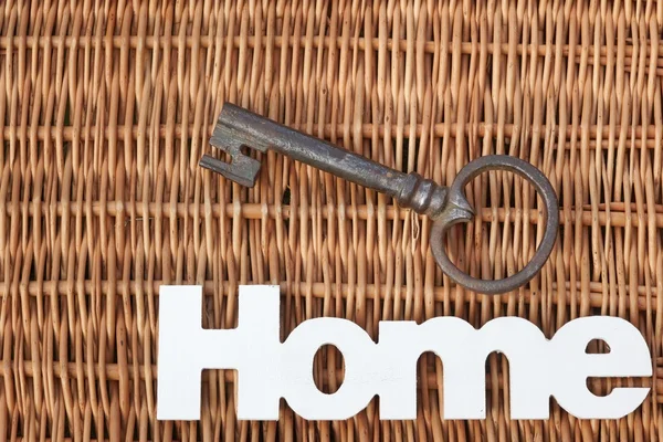 Señal de madera en casa y llave vieja sobre fondo de mimbre rústico —  Fotos de Stock