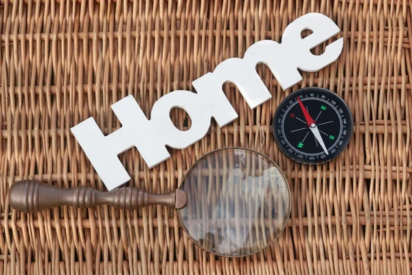 Trä skylt hem, kompass och Vintage förstoringsglas på Wicker ba — Stockfoto
