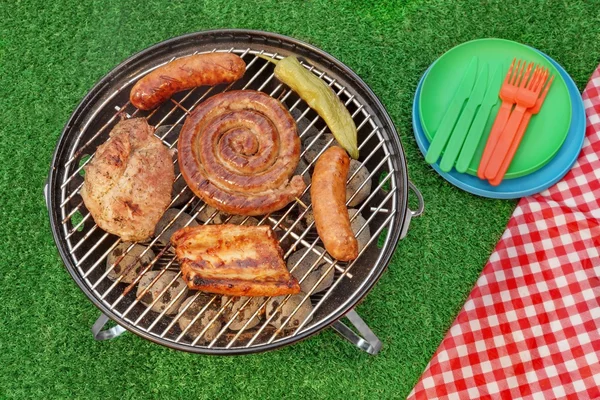 BBQ tragbarer Grill mit verschiedenen Fleischsorten und roter Picknickdecke — Stockfoto