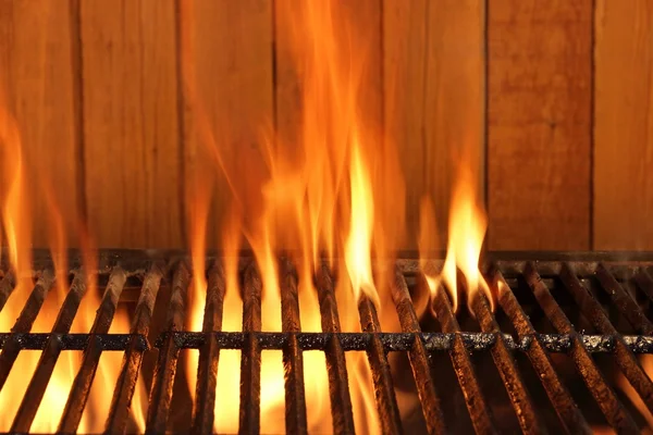 Parrilla de hierro fundido de carbón de barbacoa en llamas y fondo de madera — Foto de Stock