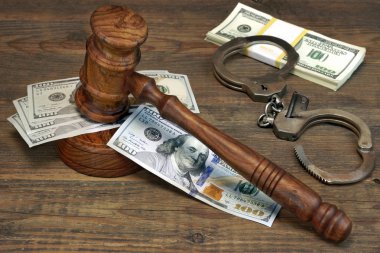 Dollar Cash, handcuffs and judge gavel on wood table clipart