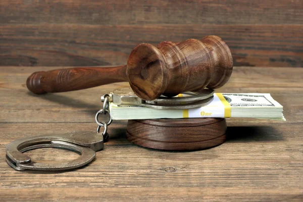 Dollar banknotes, handcuffs and judge gavel on wood table — Stockfoto