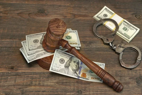 Dollar-Bargeld, Handschellen und Richtergabel auf Holztisch — Stockfoto