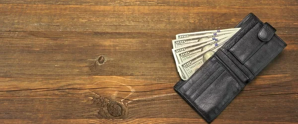 Billetera de los hombres con dinero en efectivo en dólares en el fondo de madera áspera —  Fotos de Stock
