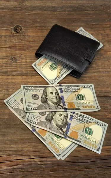 Мужской кошелек с долларовыми деньгами на грубом дереве — стоковое фото