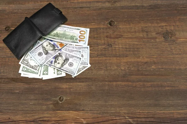 Мужской кошелек с долларовыми деньгами на грубом дереве — стоковое фото