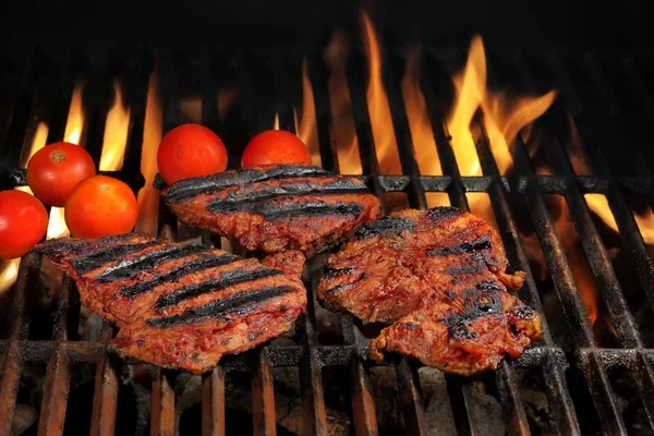 Bifes de carne na churrasqueira quente com chamas brilhantes — Fotografia de Stock