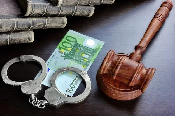 Судді молотка, наручники, євро готівкою та книги на чорний столик — стокове фото