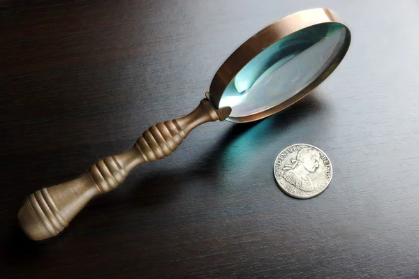 Lupa Vintage y monedas de plata antiguas en la mesa negra — Foto de Stock