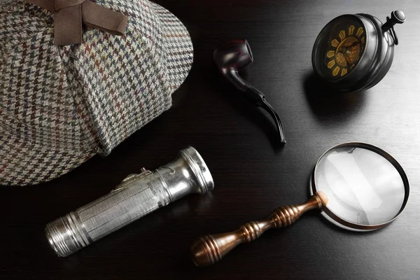 Chapeau Sherlock, clé, loupe, lampe de poche, tuyau sur la table noire — Photo