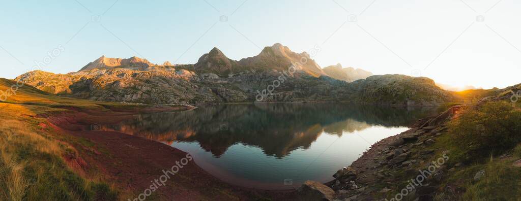 Panoramic view of mountains reflected in a lake, with a girl walking away on the left side