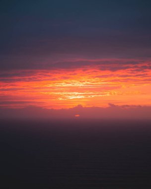 Güneş Atlantik Okyanusu 'nda bulutların ardında çok sakin bir denizle batıyor.