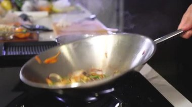 Şef, tavada dilimlenmiş salata için ızgara sebze yapıyor. Erkek bir aşçı evin mutfağında sıcak bir salata hazırlar onu kusar ve tavada karıştırır. Lezzetli bir yemek pişiriyorum. Asya yemekleri;