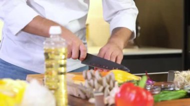 Erkek şef evde mutfakta salata hazırlıyor. Şef salata için keskin bir bıçakla havuç keser. Restoranın mutfağında lezzetli bir yemek pişirmek. Malzemelerin hazırlanması. Her gün sağlıklı yemek.