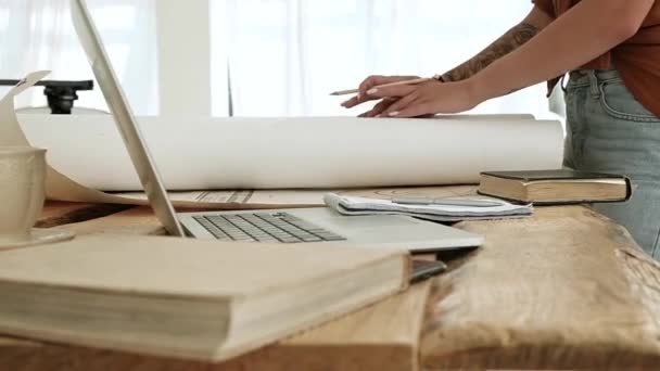 커다란 건축가 소녀는 커다란 두루마리 그림들을 노트북으로 디자이너가 디자인 프로젝트를 — 비디오