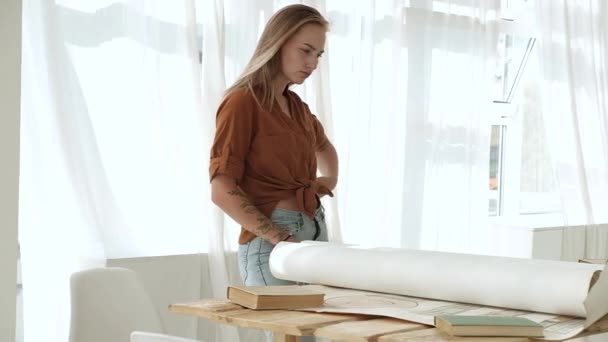 평상복을 아름다운 코카서스 여인이 사무실 공간에 계획의 커다란 두루마리들을 건축가와 — 비디오
