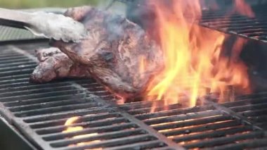 Barbekü ızgarası dışarıda kızgın demir ızgarada büyük, sulu et parçaları pişiriyor. Şef et filetosunu ızgaraya çevirmek için maşa kullanır ızgarayı ateşe, kıvılcımları ise lezzetli sokak yemekleri yapmak için kullanır..